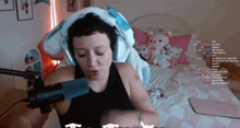 a woman wearing headphones talks into a microphone while sitting on a bed