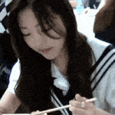 a girl with long hair is holding chopsticks in her hands