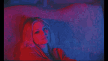a woman is laying on a bed in a dark room with red and blue lights .