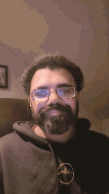a man with a beard wearing glasses and a hoodie