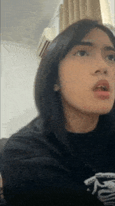 a girl wearing a black shirt with a shark on it is making a surprised face
