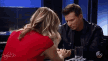 a man and woman are sitting at a table holding hands .