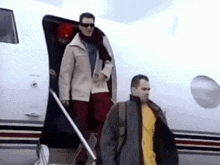 a man in a yellow shirt walks next to a man in a white jacket