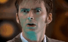 a man with blue paint on his face is making a surprised face .