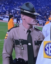 a man in a sheriff 's uniform stands on a football field