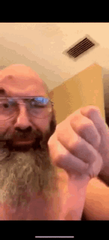 a man with glasses and a beard is giving a thumbs down sign