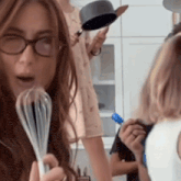 a woman wearing glasses is holding a whisk in her right hand