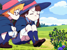 two witches are sitting in the grass looking at a plant with blueberries