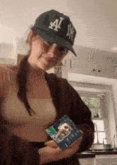 a woman wearing a ny yankees hat holds a picture of a man