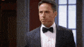 a man in a tuxedo with a bow tie looks at the camera