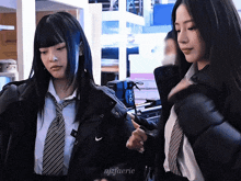 two girls in school uniforms are standing next to each other with the name njzfaerie on the bottom right