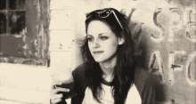 a woman is sitting in front of a wall holding a glass of beer .