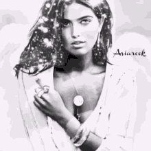 a black and white photo of a woman wearing a necklace and a watch .