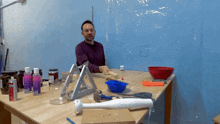 a man sits at a table with a bottle of acrylic paint