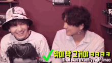 two men are sitting next to each other and one of them is wearing a bucket hat