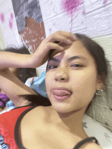 a girl sticking her tongue out in front of a brick wall