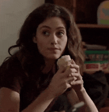 a woman is sitting at a table holding a cupcake in her hands .