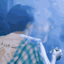 a man in a green shirt is smoking a cigarette in front of a blue background .
