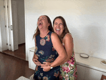 two women in floral dresses are laughing together
