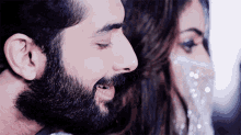 a man with a beard is smiling with his eyes closed next to a woman