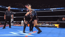 two women wrestling in a wrestling ring with a bottle of prime on the floor