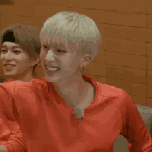 a young man in a red shirt is smiling while sitting in a chair .