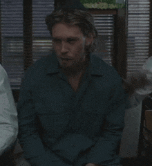 a man in a blue shirt is sitting in a chair