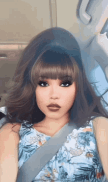 a woman wearing a floral shirt and a seat belt looks like a doll