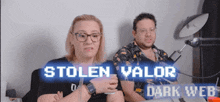 a man and a woman are sitting in front of a sign that says stolen valor