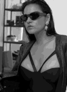 a woman wearing sunglasses and earrings is standing in front of a shelf