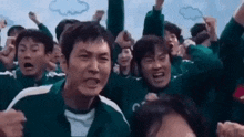 a group of people are standing next to each other with their arms in the air .
