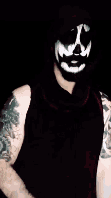 a man with a tattoo on his arm is putting a bandage on another man 's face .