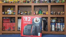 a box for a nintendo switch sits in front of a shelf filled with figurines