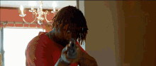 a man in a red shirt is holding a gun in his hand