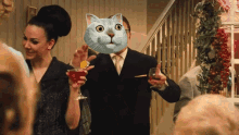 a man with a cat mask on his face is holding a martini