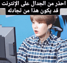 a man wearing a plaid shirt is sitting in front of a computer screen