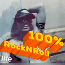 a man wearing sunglasses and a hat stands in front of a sign that says 100 % rock n roll life