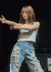 a woman in a white tank top and ripped jeans is dancing