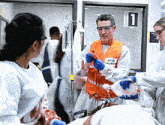 a man wearing an orange vest that says ' emergency ' on it