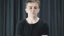 a young man in a black shirt is making a funny face .
