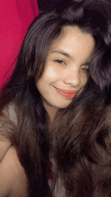 a girl with long hair is smiling and looking at the camera