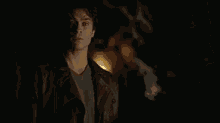 a man is standing in a dark room with a light shining on him .