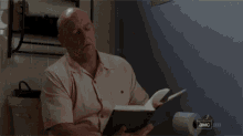 a man is looking at a piece of paper with a serious look on his face .