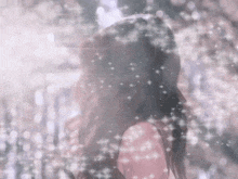 a woman in a pink dress is standing in front of a window with snow falling on her .