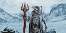 a man with a beard is holding a trident in front of a snowy mountain