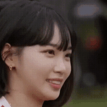 a close up of a woman 's face with short hair and earrings smiling .