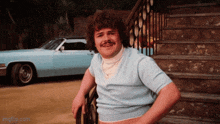 a man with a mustache is leaning on a railing in front of a car