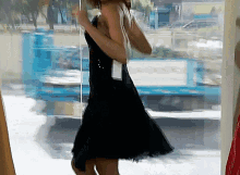 a woman in a black dress is standing in front of a window with a sign that says ' elise ' on it