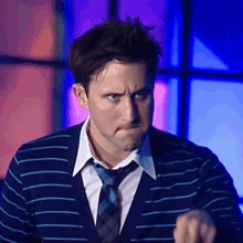 a man wearing a striped shirt and tie making a funny face