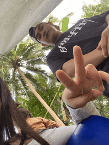 a man wearing a shirt that says ' aloha ' on it giving the middle finger